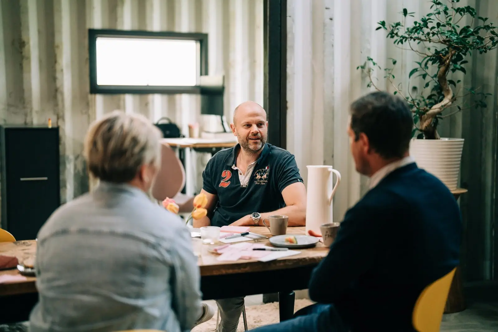 Tre personer i samtal runt ett bord med post-it-lappar